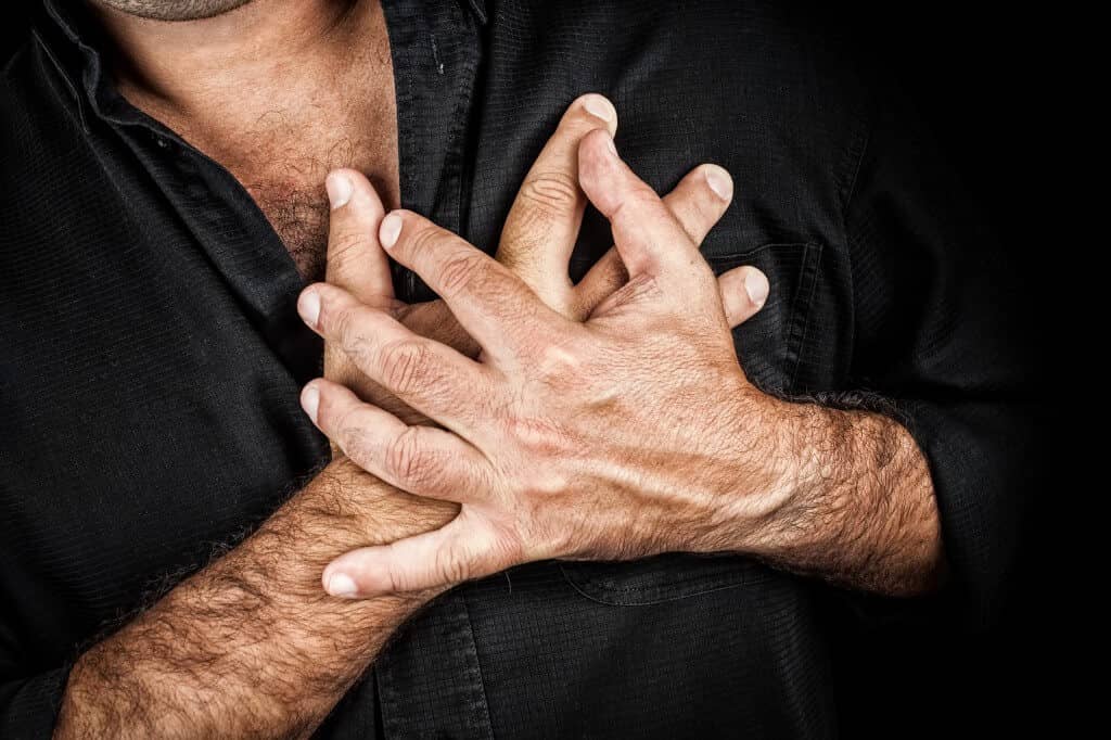 Close up of two hands grabbing a chest on a black background, us