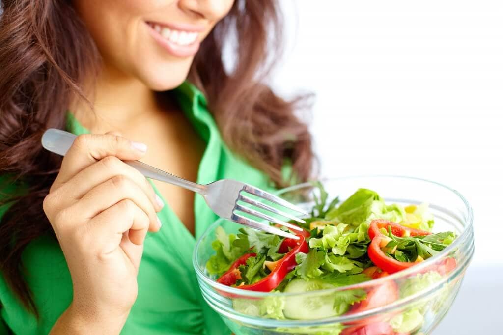 Close-up of pretty girl eating fresh vegetable salad