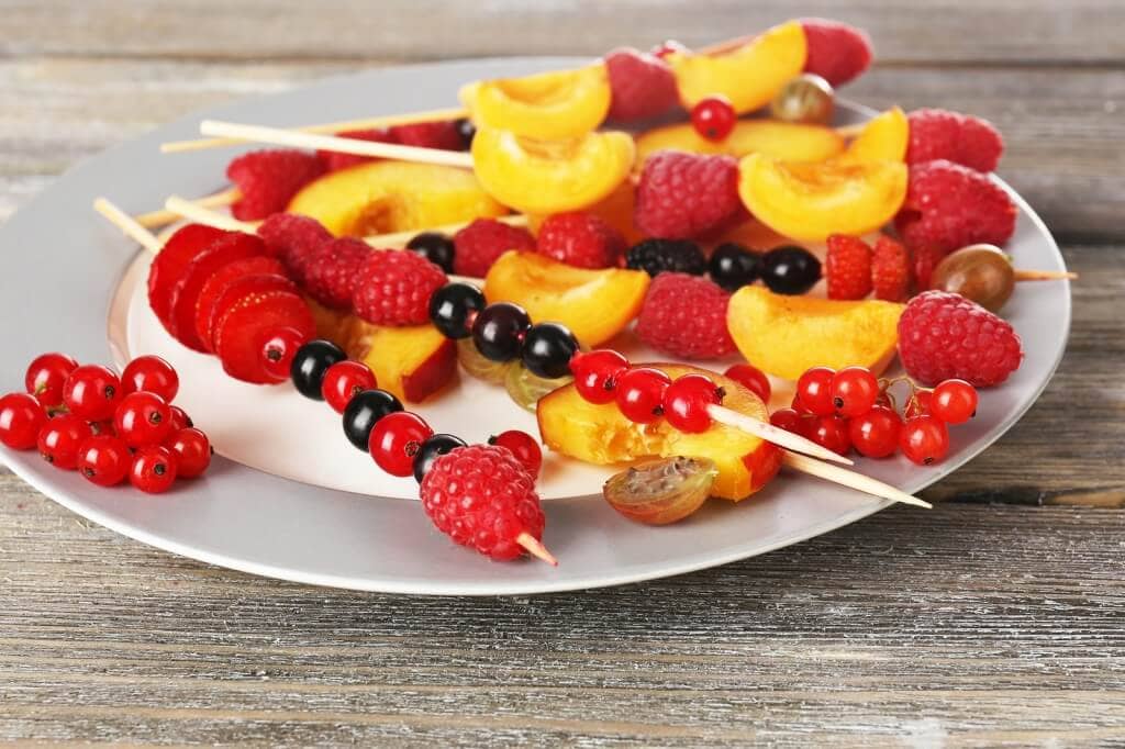 Fresh fruit skewers for healthy snack on wooden table close up